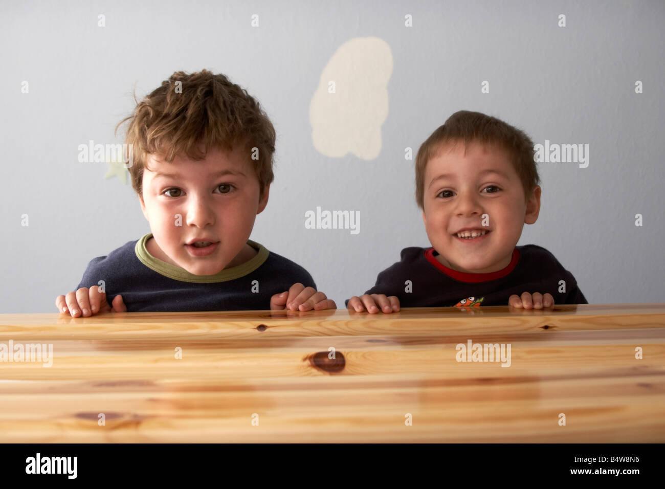 Due giovani ragazzi bambini fratelli guardando oltre il bordo di un letto di NAOH CJWH divertente divertente comico divertente Foto Stock