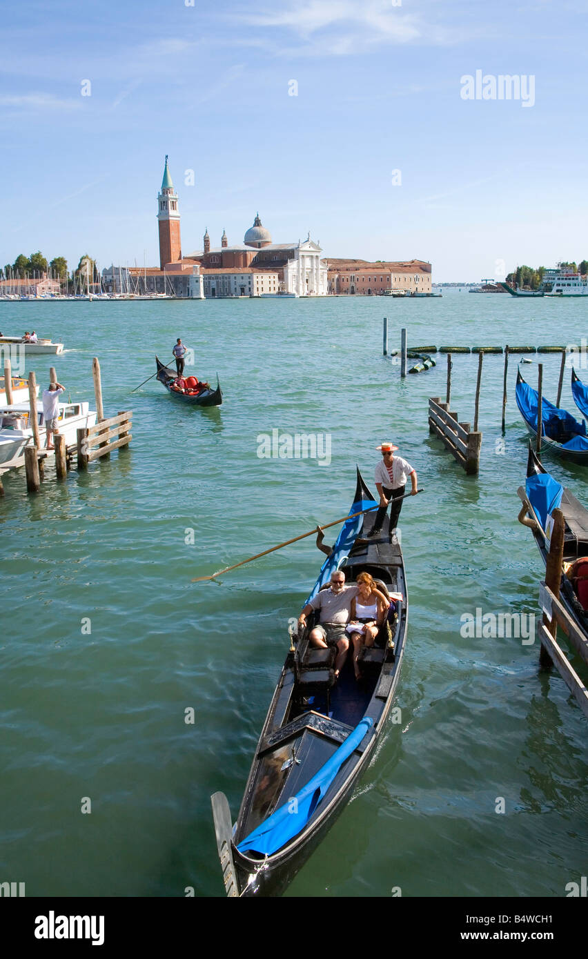 Giovane prendere un giro in Gondola con la Basilica di San Giorgio Maggiore attraverso la laguna in background Foto Stock