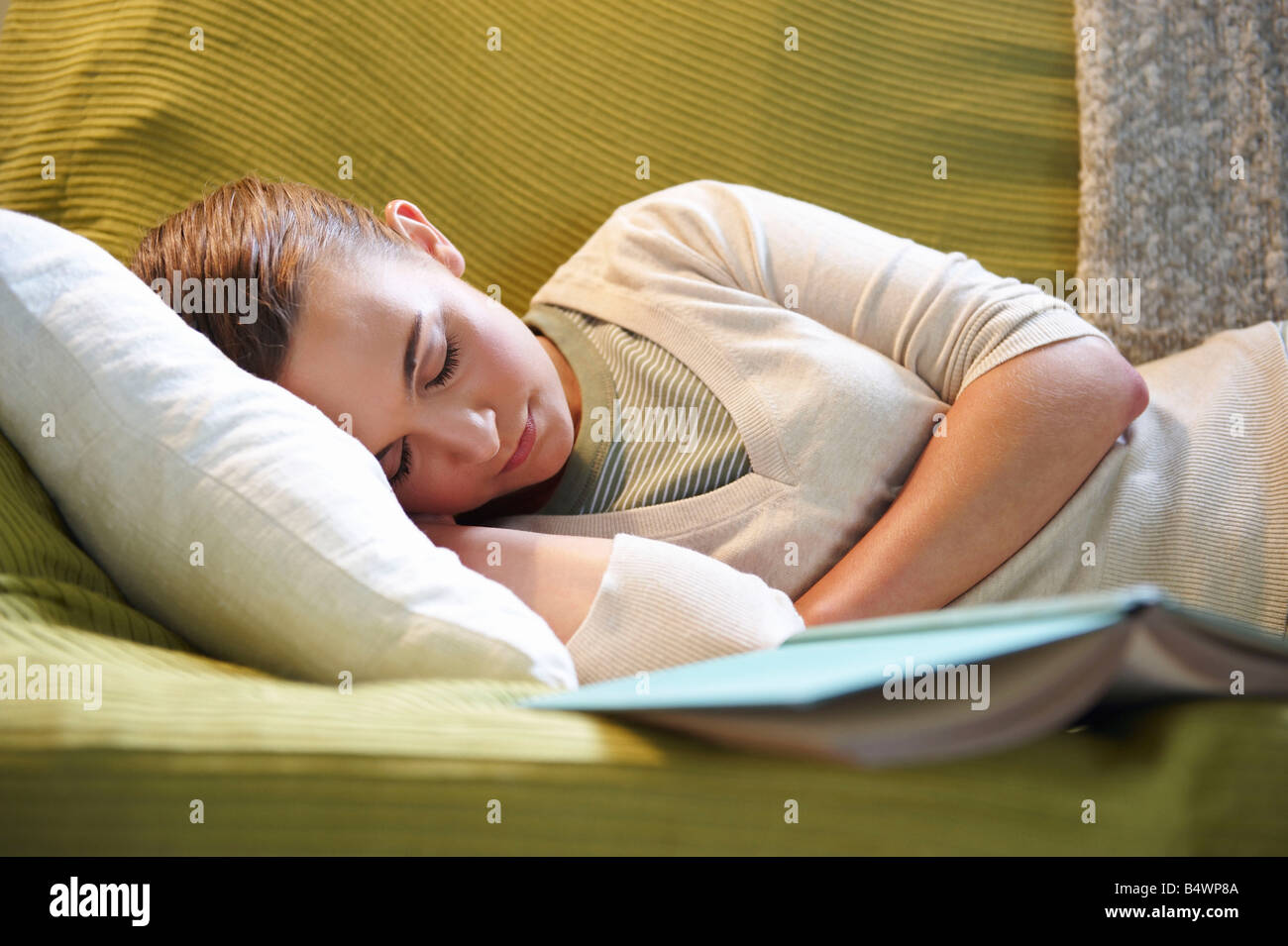 Giovane donna disteso sul lettino, con libro Foto Stock