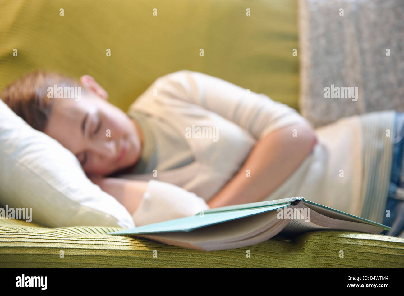 Giovane donna disteso sul lettino, con libro Foto Stock