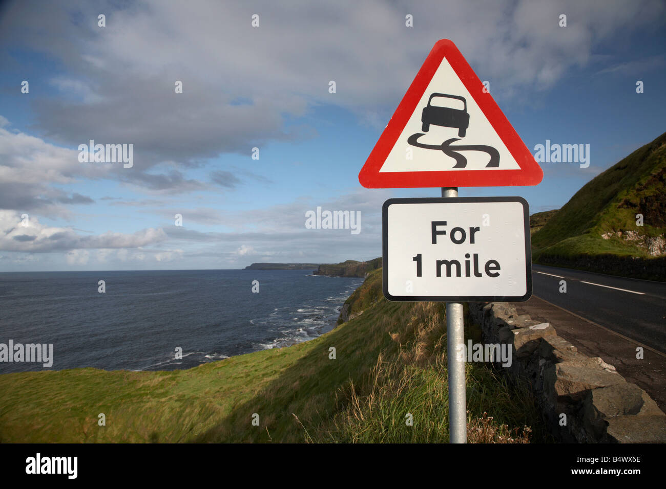 Strada sdrucciolevole pericolo rosso triangolo di avvertimento per 1 miglio segno sulla famosa A2 North Antrim causeway Coastal road route Foto Stock