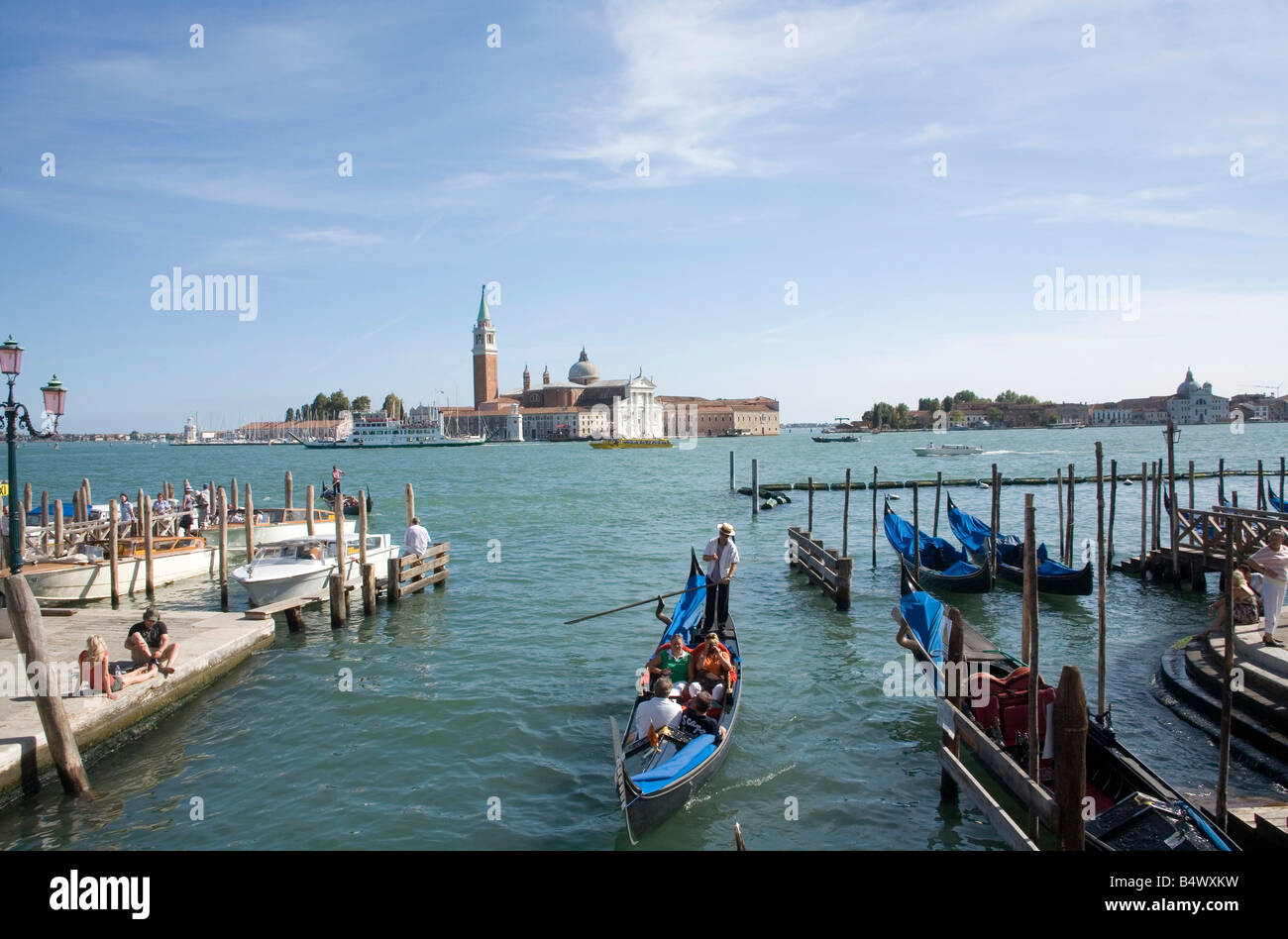Persone che fanno un giro in gondola con la Basilica di San Giorgio Maggiore attraverso la laguna in background Foto Stock