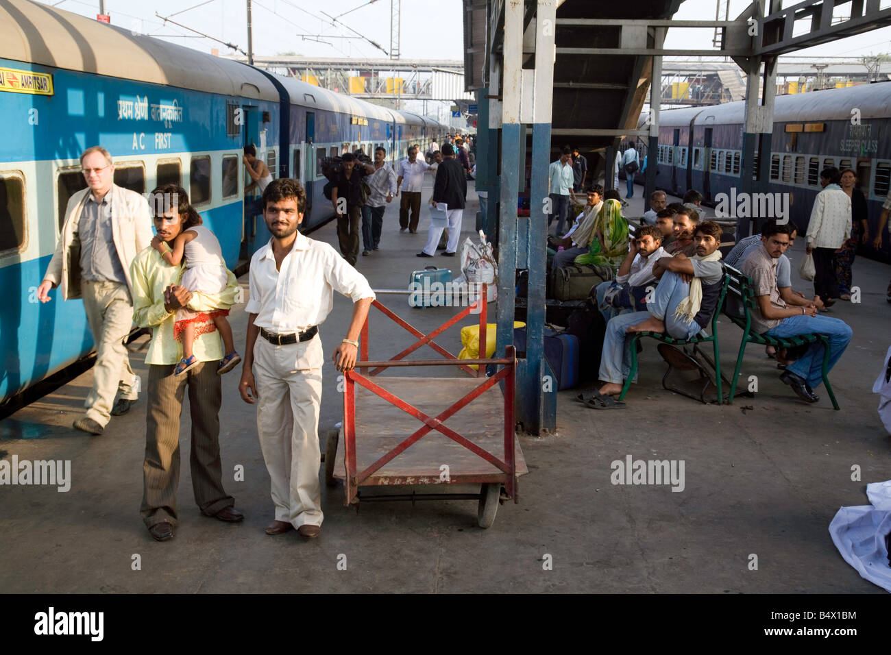 Pendolari attendere sulla piattaforma per i treni a nuova stazione di Delhi, India Foto Stock