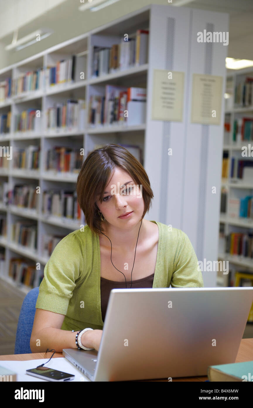 Giovane donna che lavorano su computer portatile in biblioteca Foto Stock