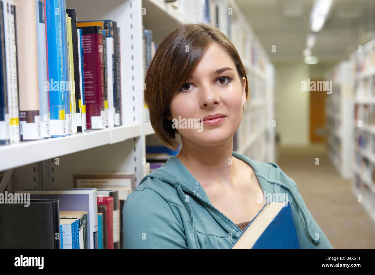 Giovane donna con il libro della biblioteca Foto Stock
