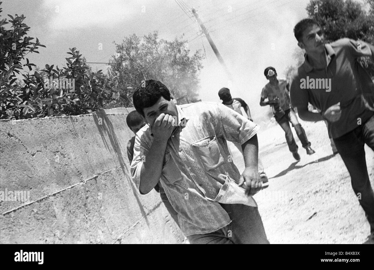 Alcuni uomini palestinesi scappare da un gas lacrimogeni attacco da parte dell'esercito israeliano o i.d.f Foto Stock