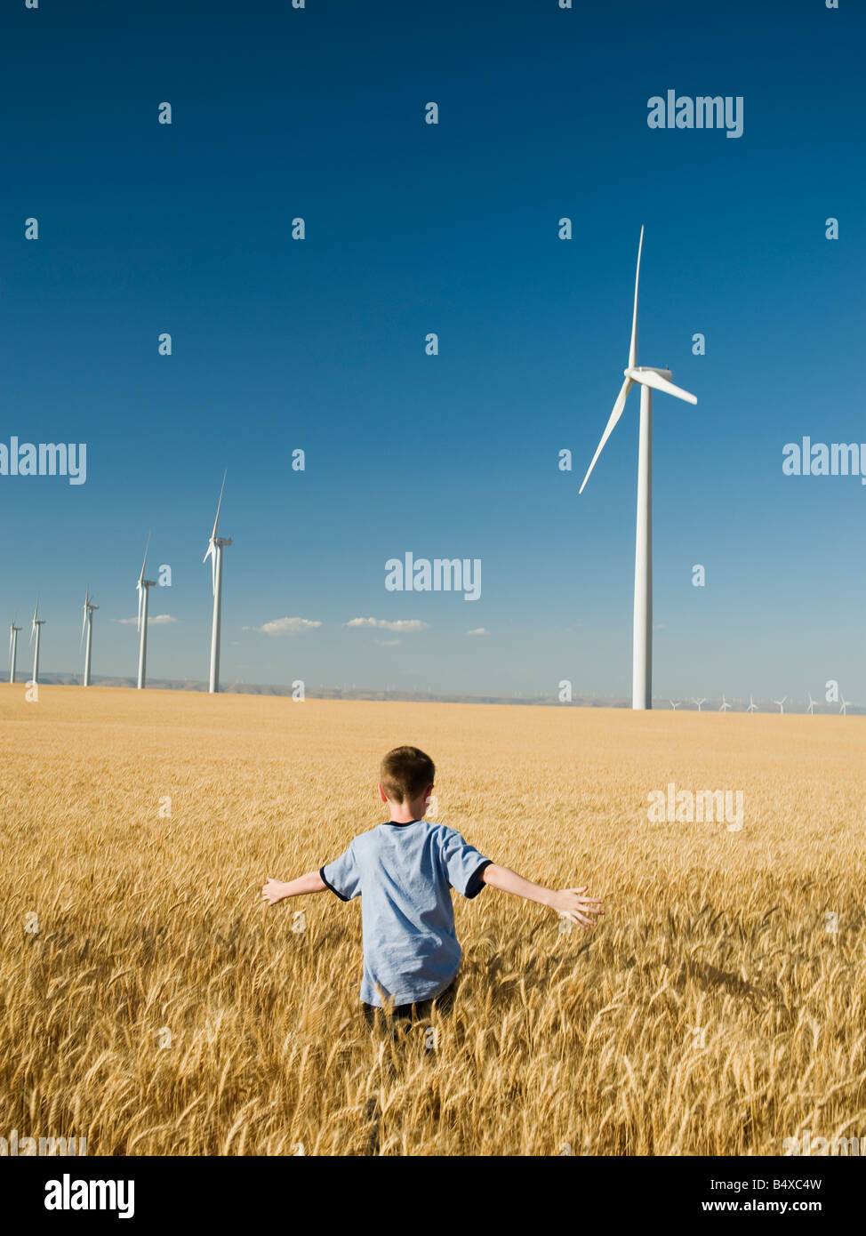 Ragazzo in esecuzione tramite il campo su wind farm Foto Stock