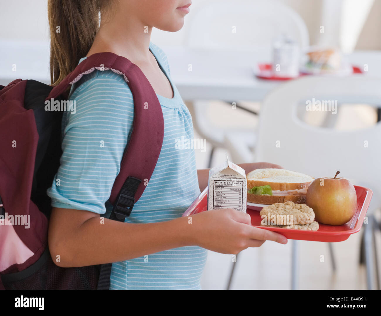 La ragazza che porta il vassoio pranzo a scuola Foto Stock