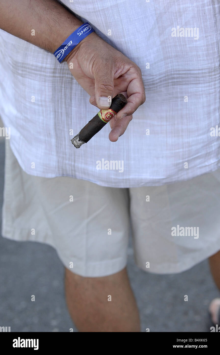 Un uomo che indossa pantaloni corti e una camicia di lino fuma un sigaro  Foto stock - Alamy