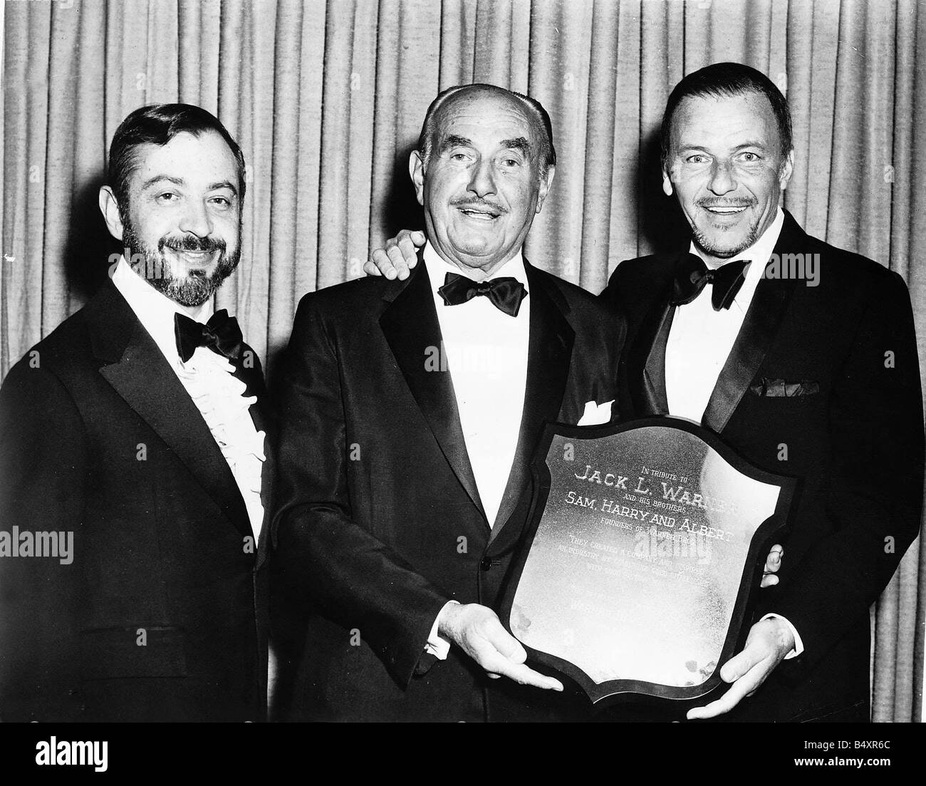 Frank Sinatra con gli amici in possesso di una protezione per il tributo della Warner Brothers Foto Stock