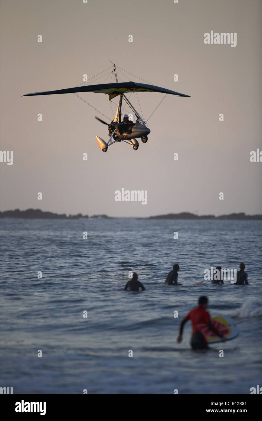 Microlite volare sopra il mare e surfisti a rocce bianche beach in Portrush al tramonto Irlanda del Nord Foto Stock