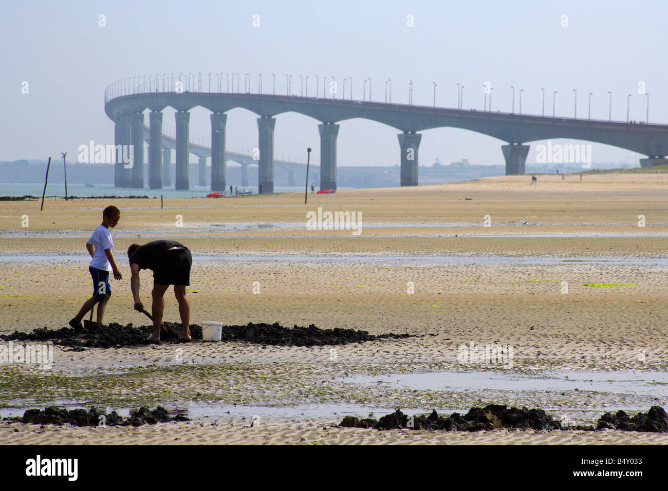 Padre e figlio Spalare la sabbia con ponte in background Foto Stock