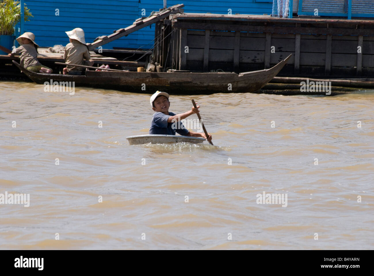 Un giovane stateless rifugiati vietnamiti ragazzo arriva in una ciotola flottante per ricevere donazioni di cibo dai turisti Foto Stock