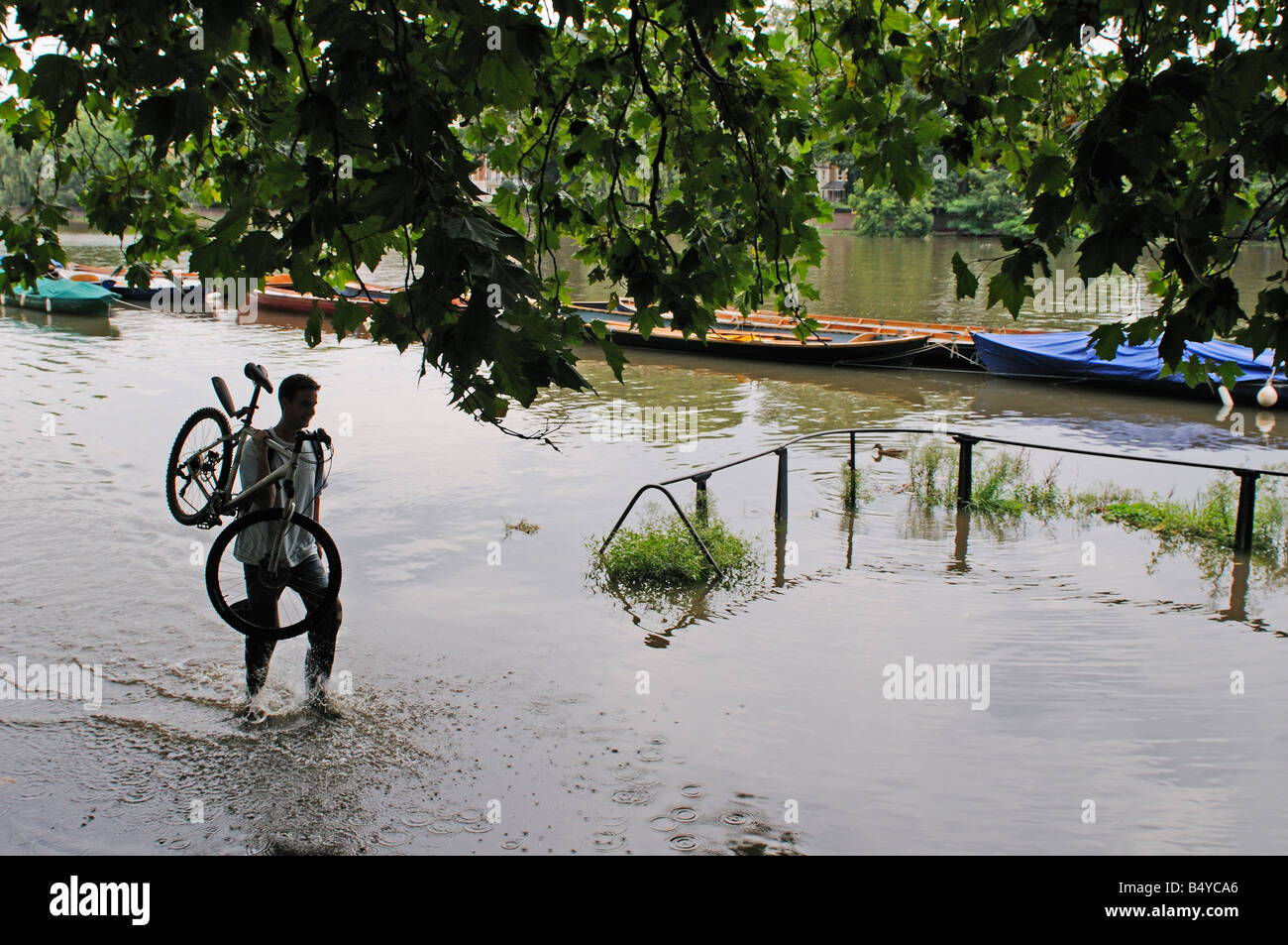 Uomo che porta la sua bicicletta attraverso inondati di acqua sul percorso nel centro di Richmond Foto Stock