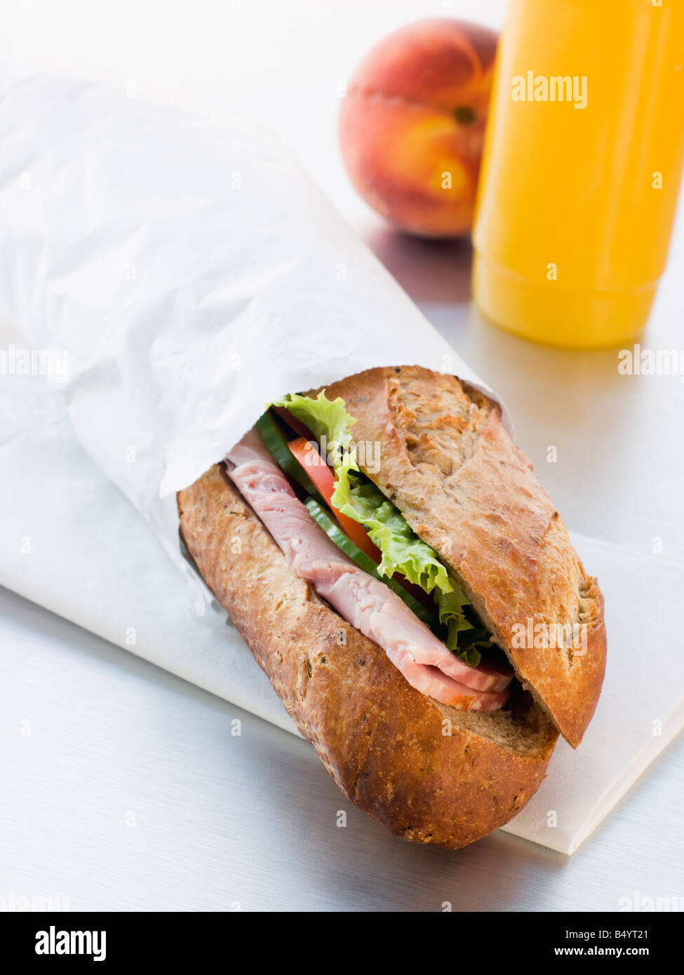 Prosciutto e insalata granaio baguette con mango e il frullato di banana e le pesche noci Foto Stock