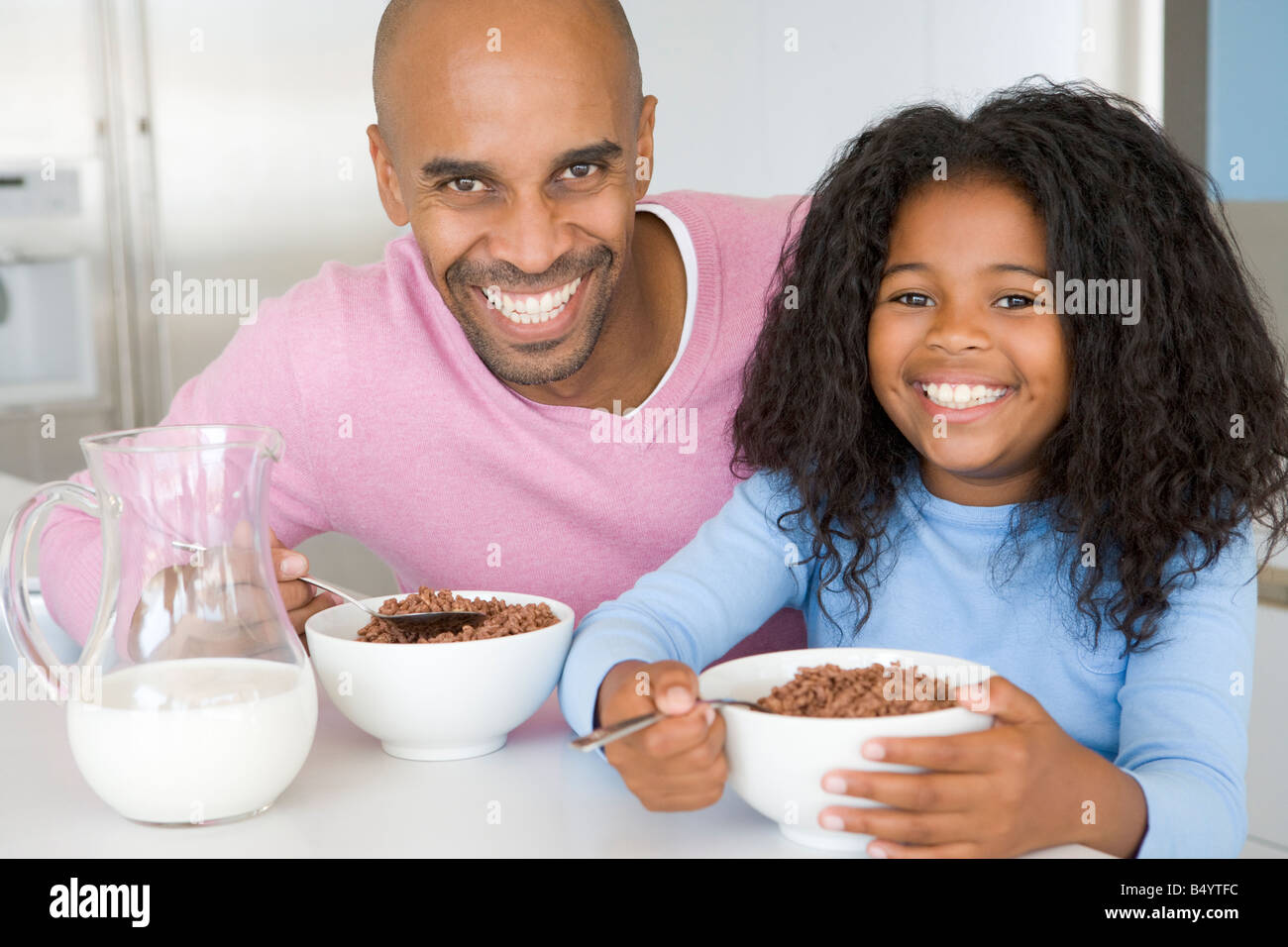 Padre seduto con la figlia come lei devono mangiare la prima colazione Foto Stock