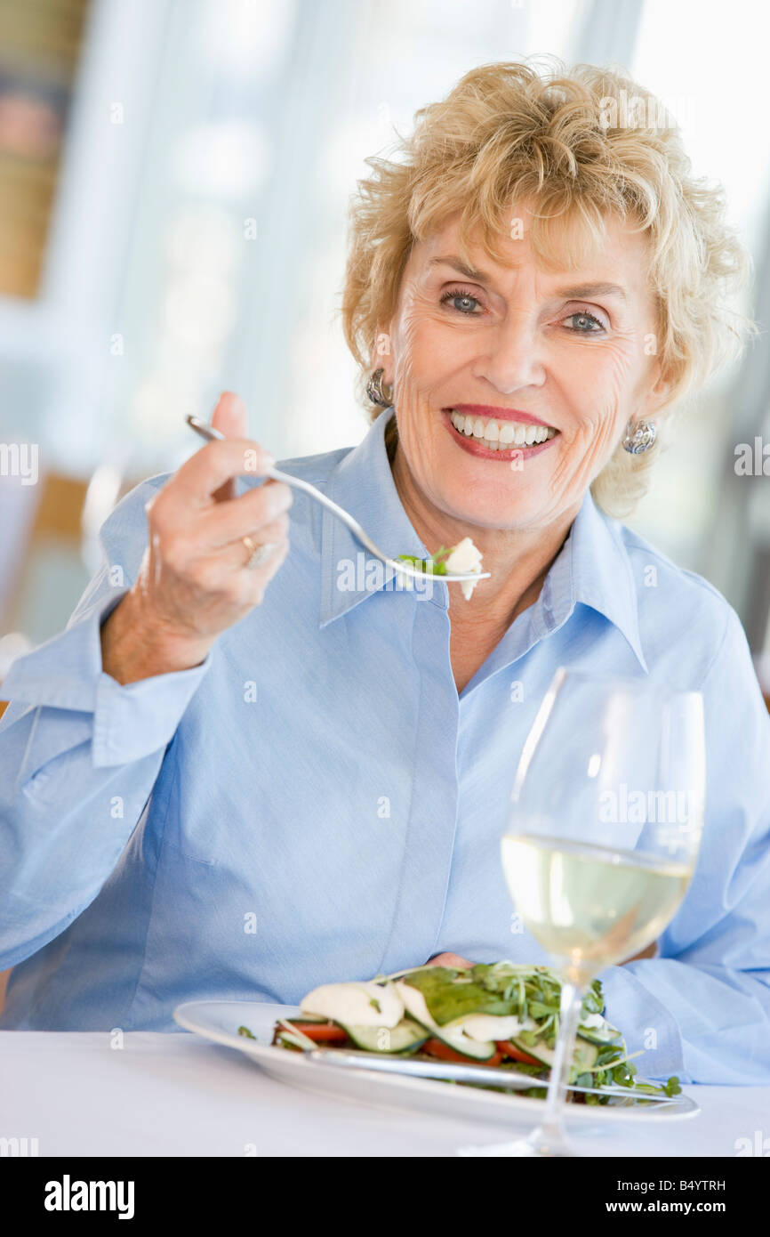 Donna godendo il pasto con un bicchiere di vino Foto Stock