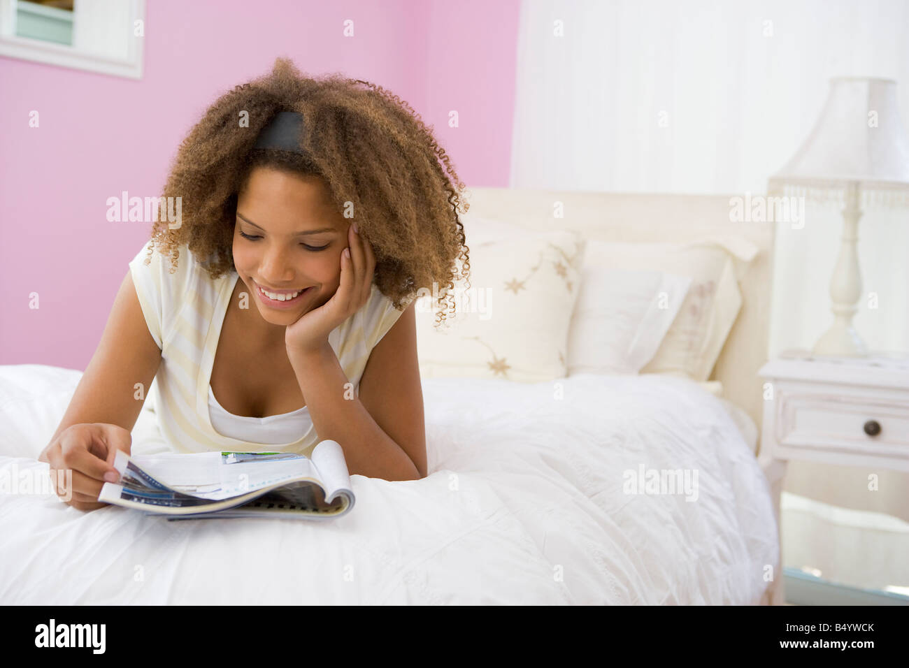 Ragazza adolescente giacente sul letto la lettura Foto Stock