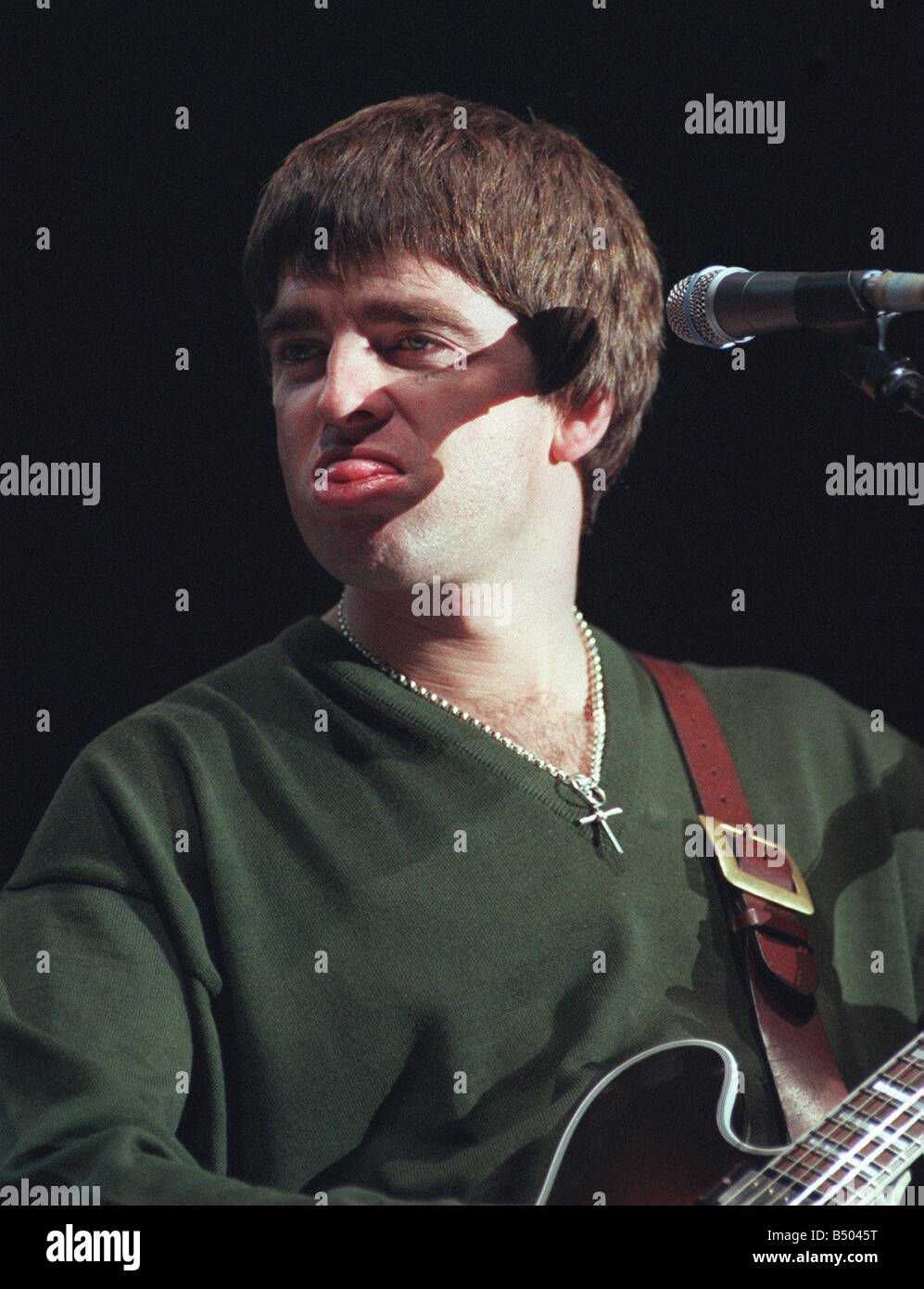 Noel Gallagher Oasis gruppo pop Dicembre 1997 con la lingua fuori a suonare la chitarra microfono Foto Stock