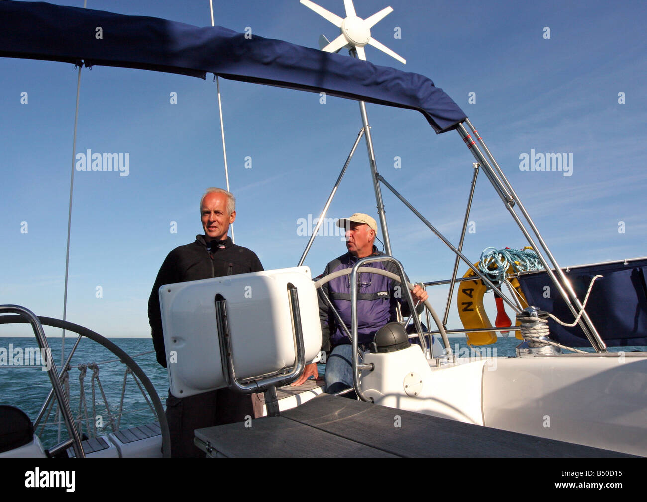 Skipper e il suo compagno helming yacht Namaste in mare su una luminosa giornata di sole Foto Stock