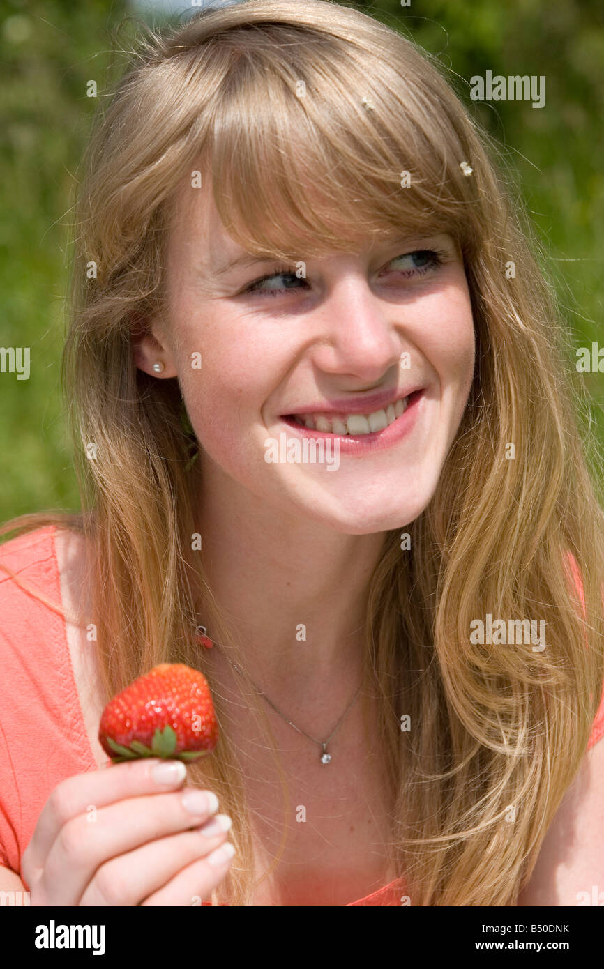 Le donne mangiare una fragola - Frau ißt einen Erdbeerel - gesundes Obst Foto Stock