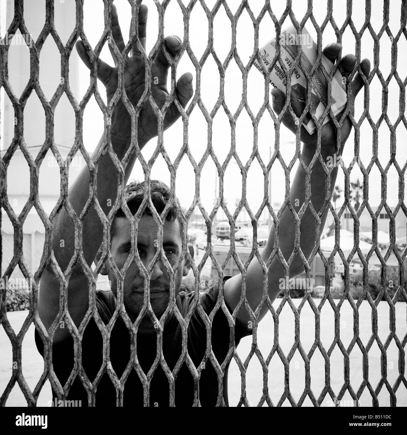 Uomo messicano con le mani contro il confine internazionale. Foto Stock