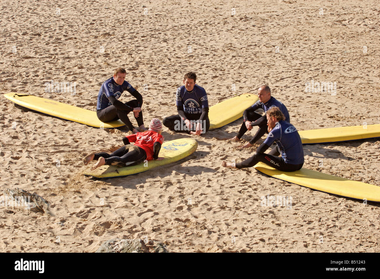 Ragazza istruttore di surf dalla estrema Academy a Watergate Bay vicino a Newquay, Cornwall, insegnare nozioni di base sulla spiaggia Foto Stock