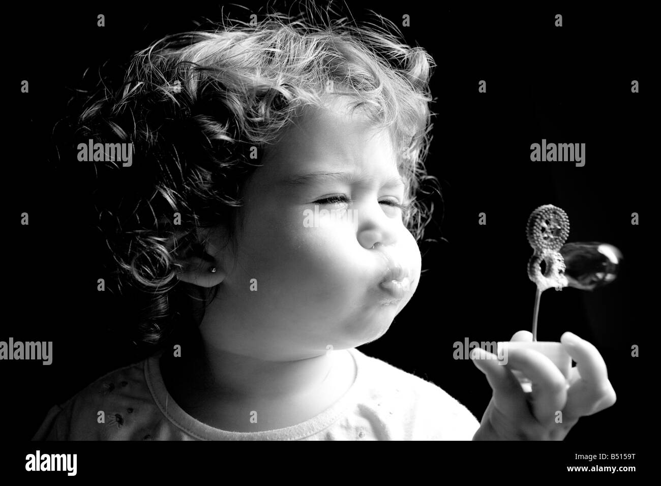 Una bambina soffiando bolle di sapone con una bacchetta Foto Stock