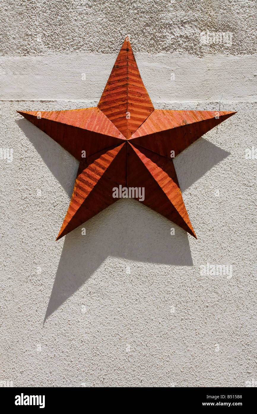 Metallo rosso paese rustico stella appesa su una parete esterna Foto Stock