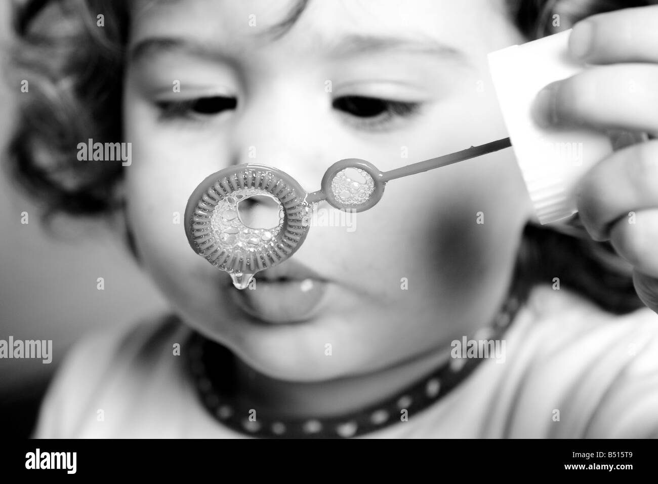Una bambina soffiando bolle di sapone con una bacchetta Foto Stock