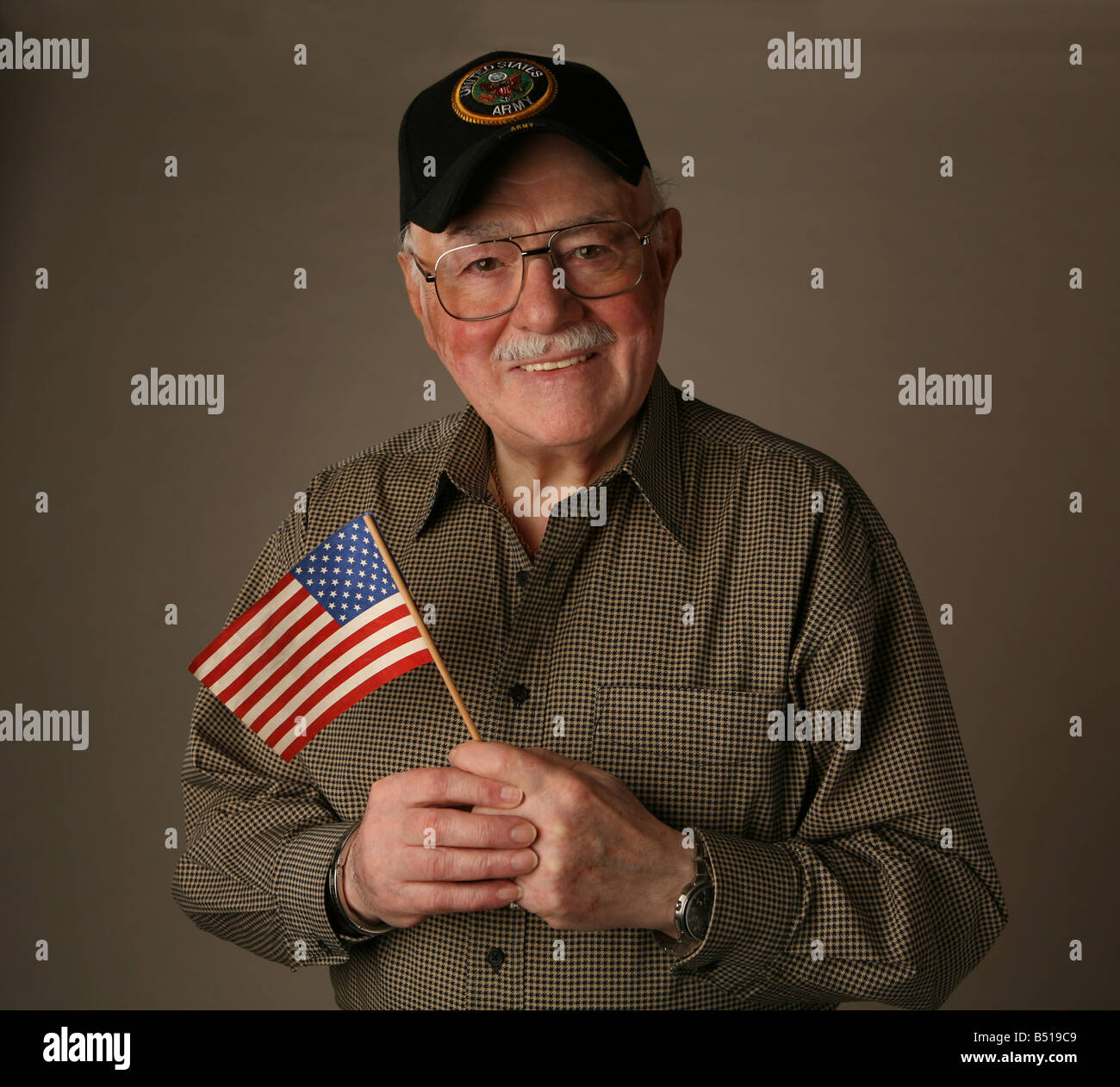 Anziani American II Guerra Mondiale veterano tenendo una bandiera americana e indossando un esercito degli Stati Uniti cap. Foto Stock