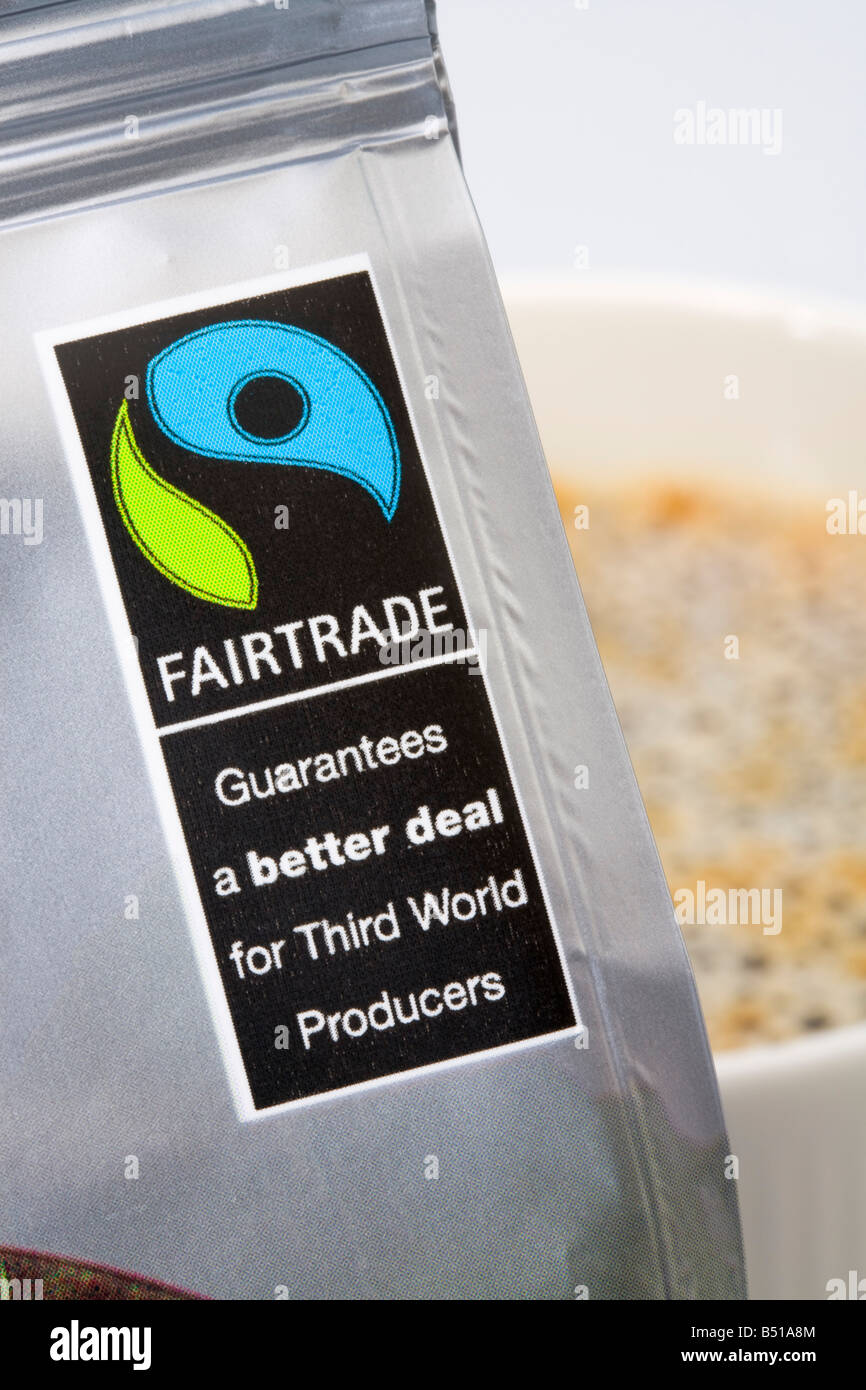 Close up Fairtrade etichetta e logo sul caffè macinato pacchetto con mug dietro. Inghilterra Regno Unito Gran Bretagna Foto Stock