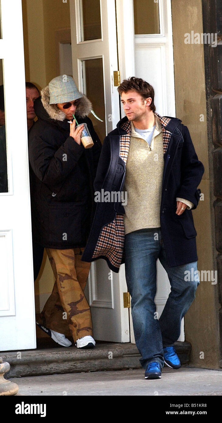 Robbie Williams undicesimo marzo 2002 in hat sul Royal Mile di Edimburgo questo pomeriggio nella foto con l'attore Jonathan documento Wilkes in duffle coat acquistare un kilt di bere il caffè attraverso una paglia Foto Stock