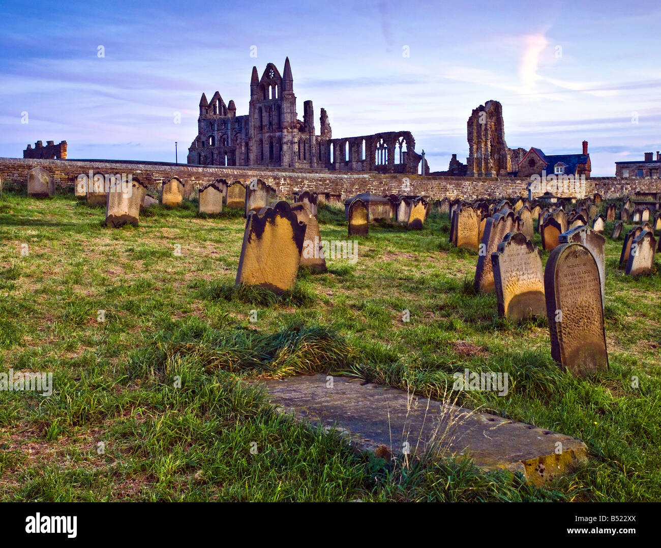 Whitby Abbey e Chiesa di Santa Maria cimitero al tramonto Foto Stock