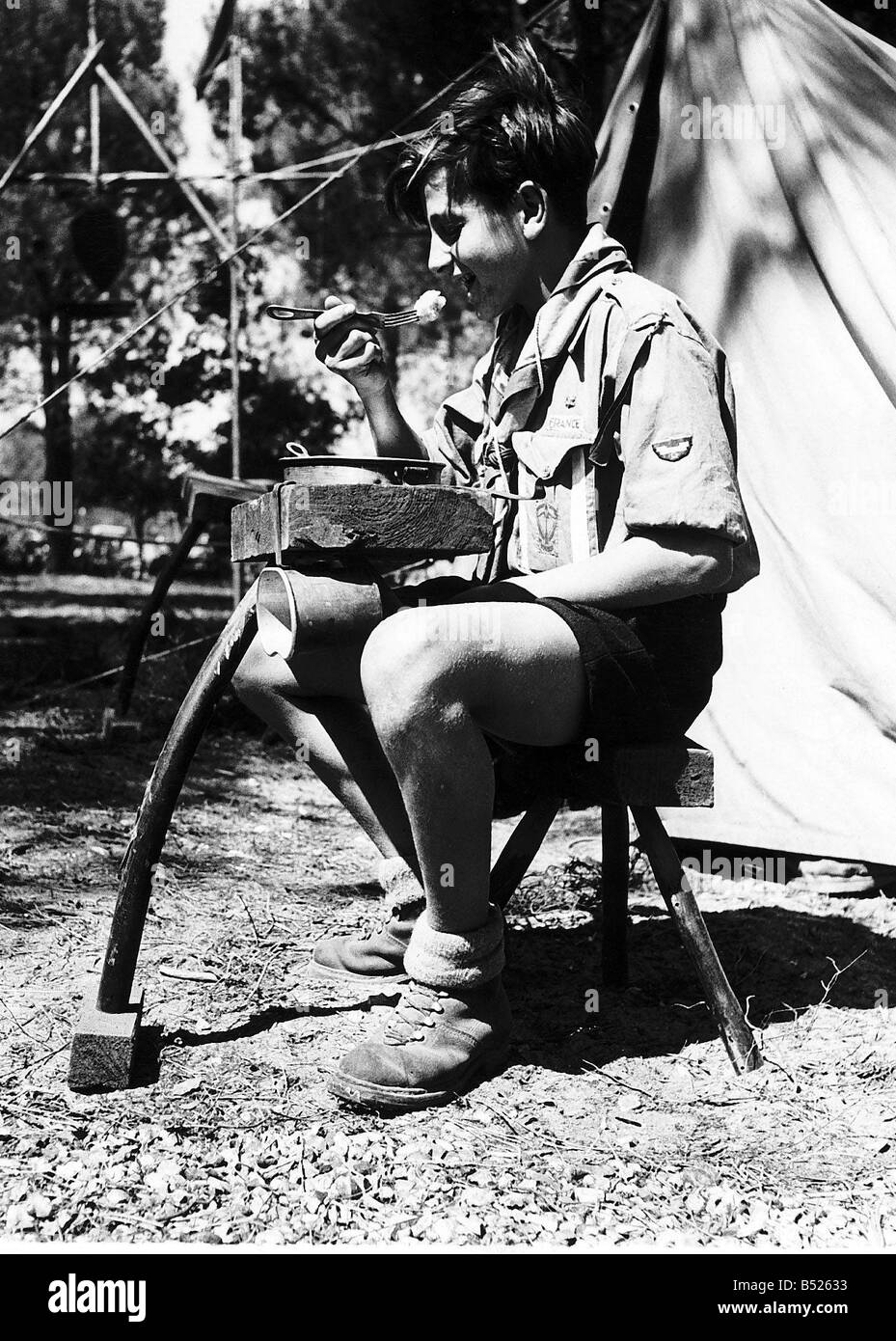 Un francese di boy scout che frequentano gli Scout Jamboree mondiale che è in Moisson vicino a Parigi egli è qui le immagini di mangiare il suo cibo Udienza Sua fatto a mano tavolo e sgabello vicino alla sua tenda Foto Stock