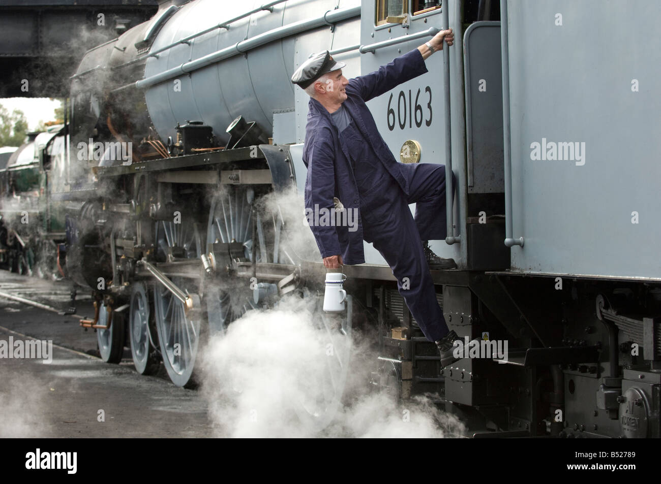 Un motore a vapore guidatore sale nella sua cabina. Il treno è 60163 Tornado, sulla Grande Stazione Centrale. Foto Stock