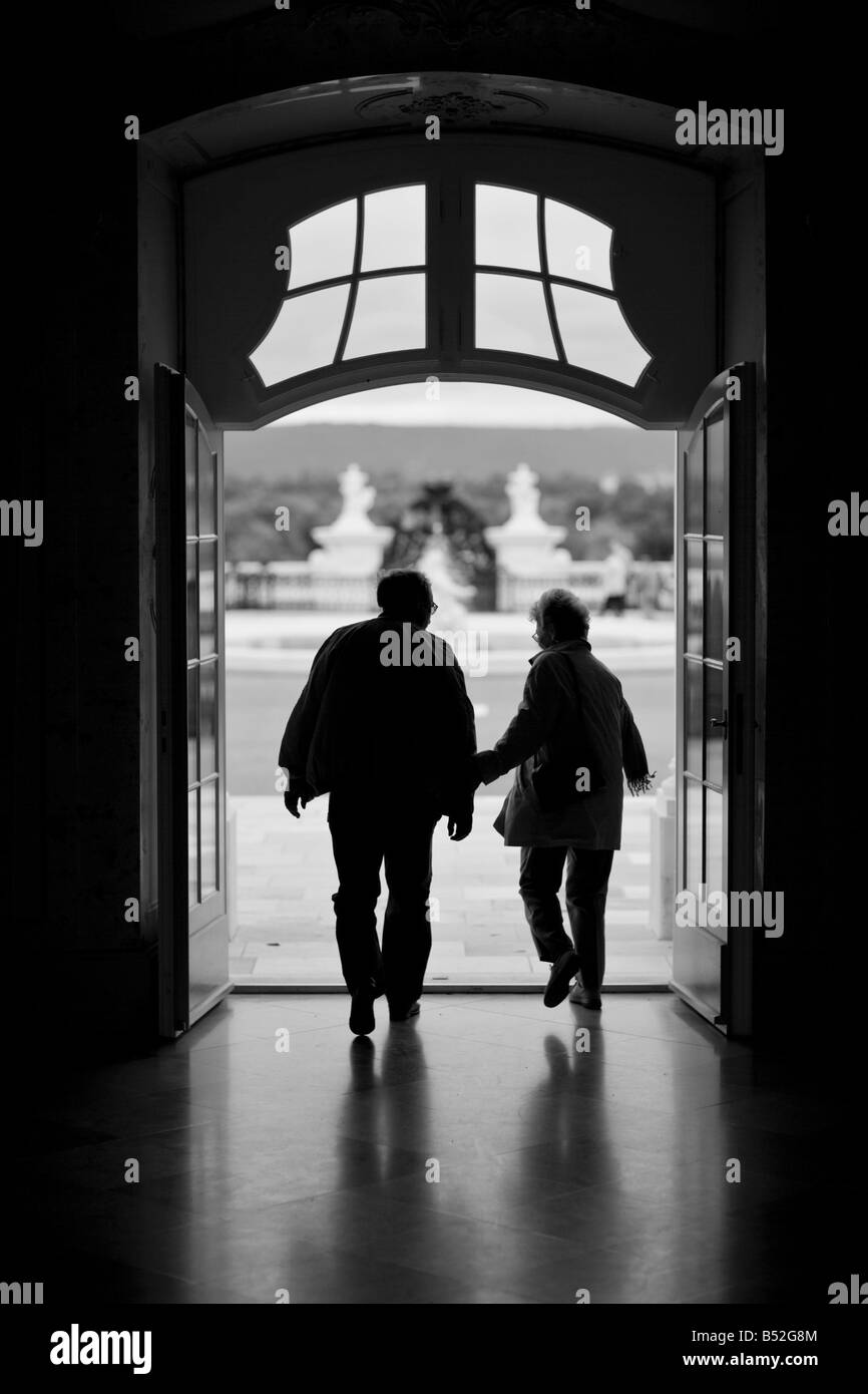 Silhouette di Coppia matura a piedi attraverso un portale scuro verso la luce. Foto Stock