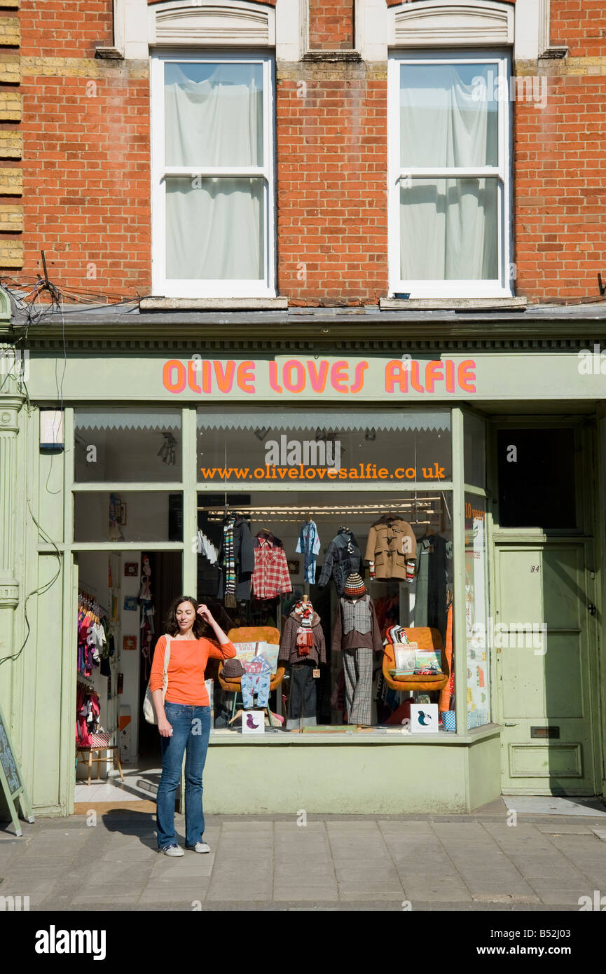 Una donna si erge al di fuori "Oliva Alfie ama' kid's lifestyle boutique e negozio di abbigliamento in Church street a Stoke Newington Hackney Foto Stock