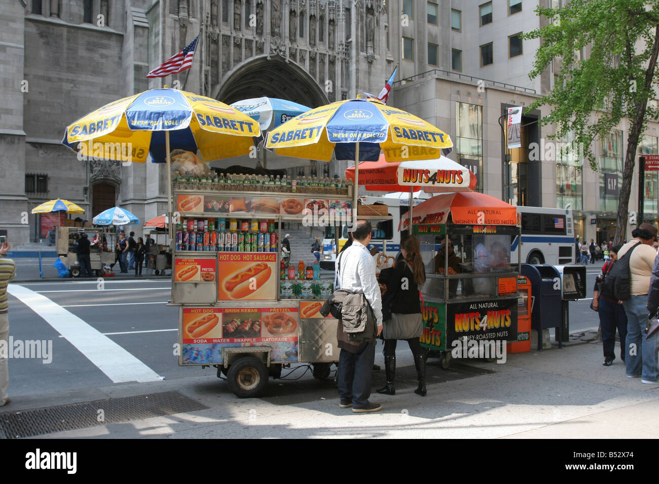 Gente che compra un pretzel da un fornitore del cane caldo in Midtown Manhattan. Accanto a loro è un fornitore che vende i dadi canditi. New York, 4 maggio 2008 Foto Stock