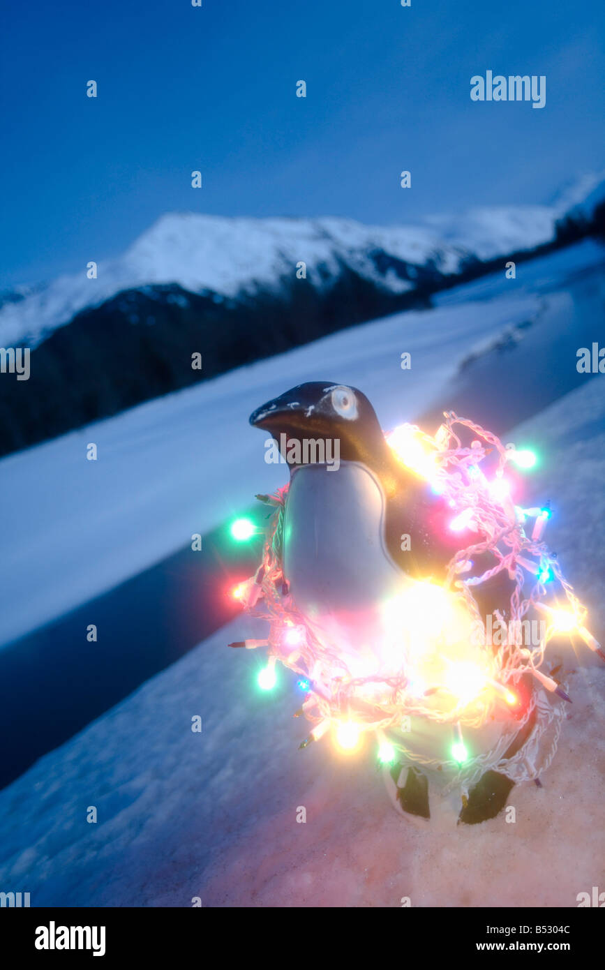 Pinguino di plastica avvolto in albero di Natale luci sulla seduta riverbank inverno Alaska Foto Stock