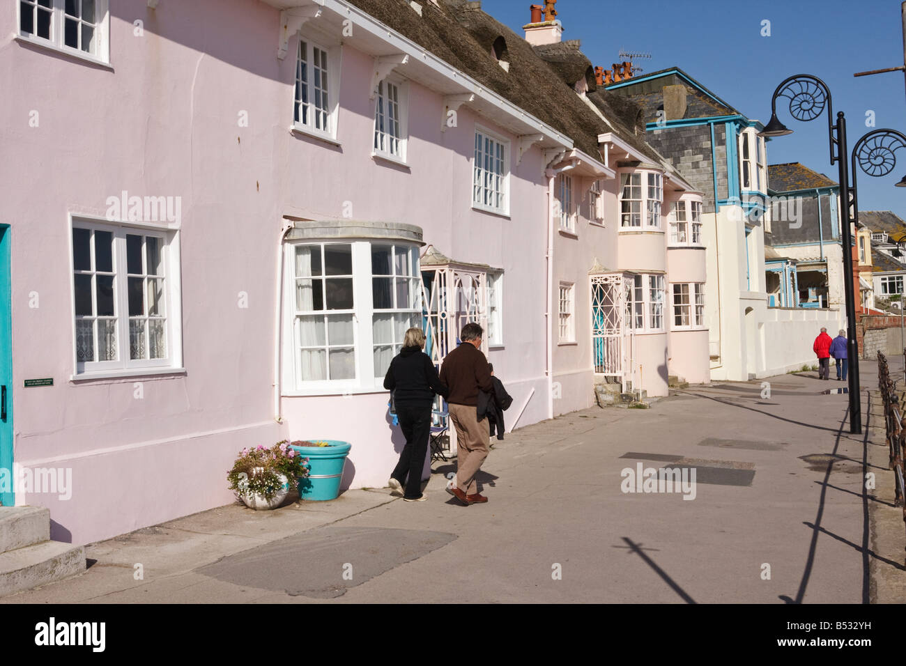 Una coppia di visitatori a piedi passato cottage storica del XIX secolo e la versione precedente di Lyme Regis Dorset Foto Stock