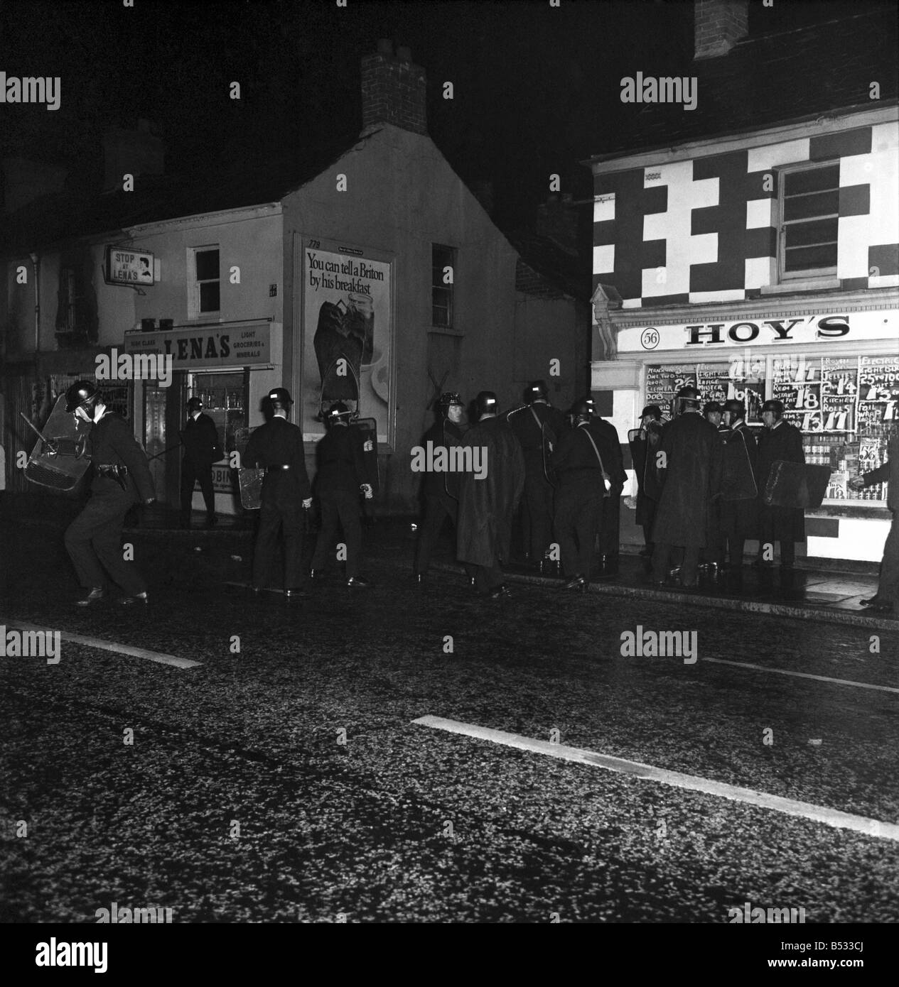 Irlanda del Nord Belfast Falls Road Agosto 1969. Poliziotto in piedi con la mitragliatrice; e benzina esplodere bombe round ca blindati Foto Stock