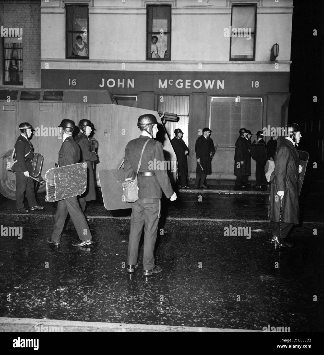 Irlanda del Nord Belfast Falls Road Agosto 1969. Poliziotto in piedi con la mitragliatrice; e benzina esplodere bombe round ca blindati Foto Stock