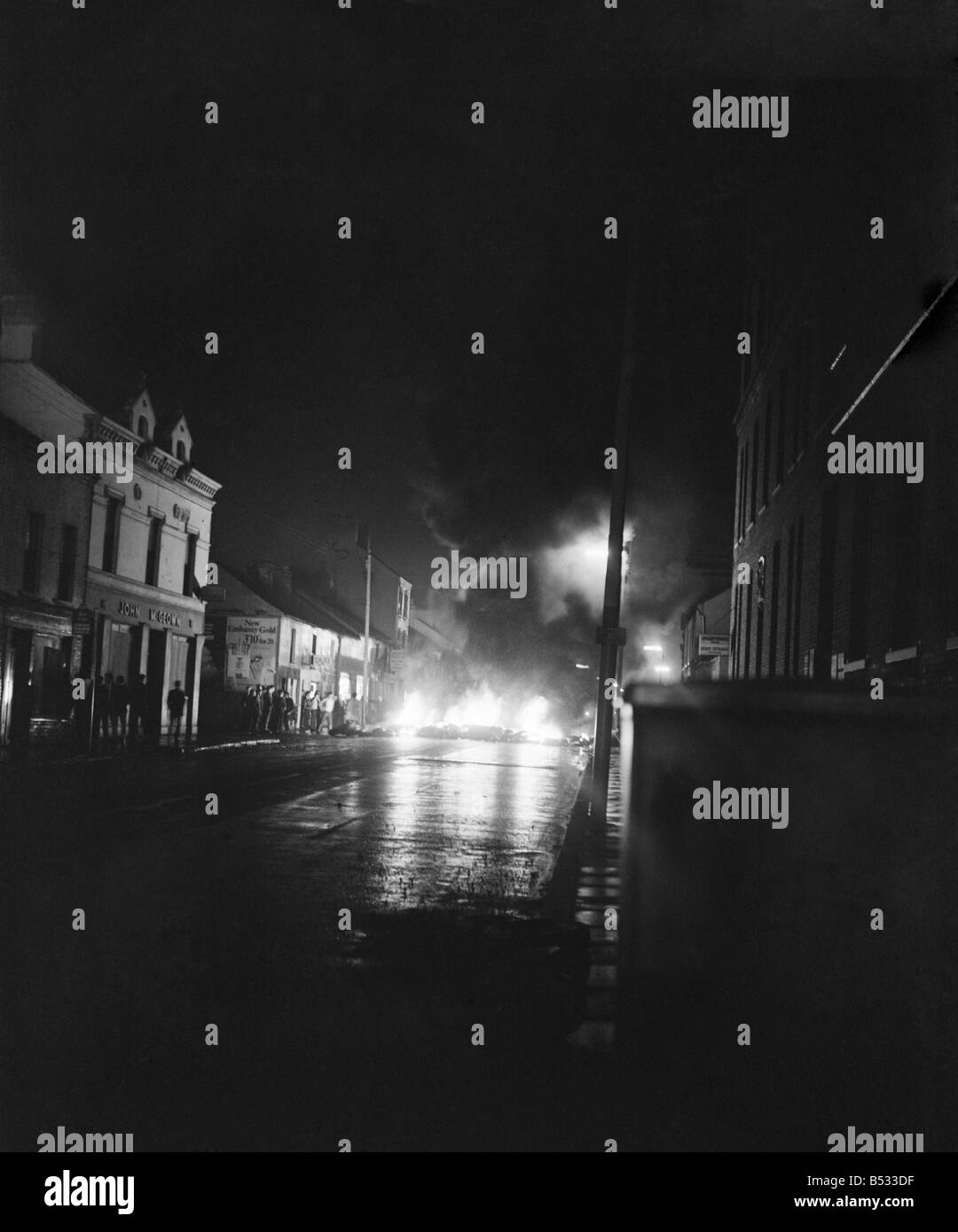 Irlanda del Nord Belfast Falls Road Agosto 1969. Poliziotto in piedi con la mitragliatrice; e benzina esplodere bombe round ca blindati Foto Stock