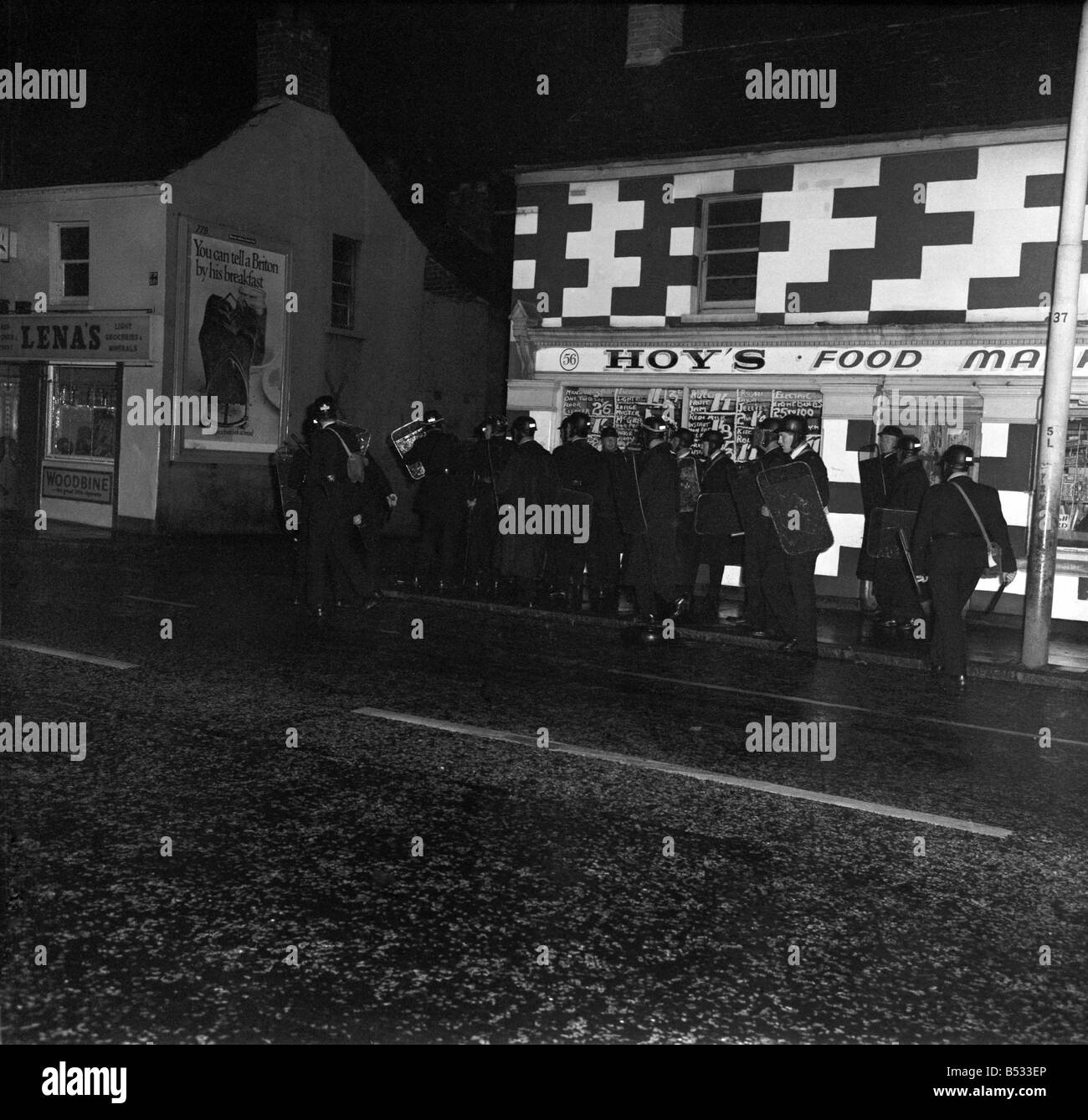 Irlanda del Nord Belfast Falls Road Agosto 1969. Poliziotto in piedi con la mitragliatrice; e benzina esplodere bombe round ca blindati Foto Stock