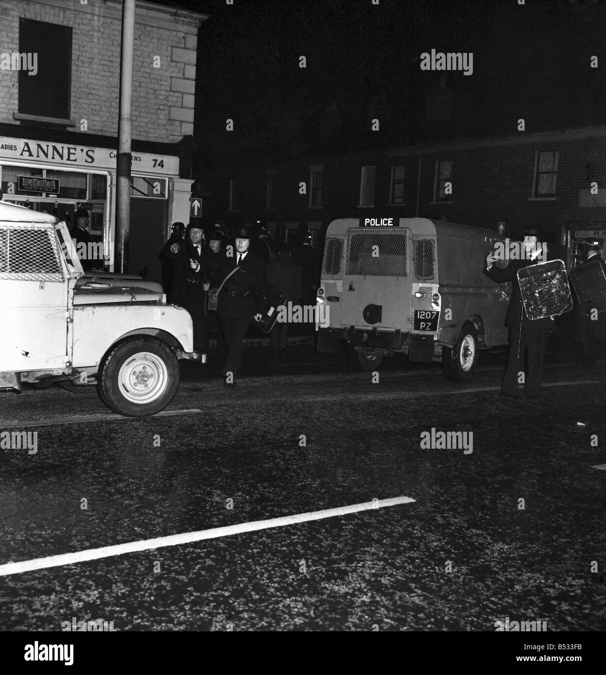 Irlanda del Nord Belfast Falls Road Agosto 1969. Poliziotto in piedi con la mitragliatrice; e benzina esplodere bombe round ca blindati Foto Stock