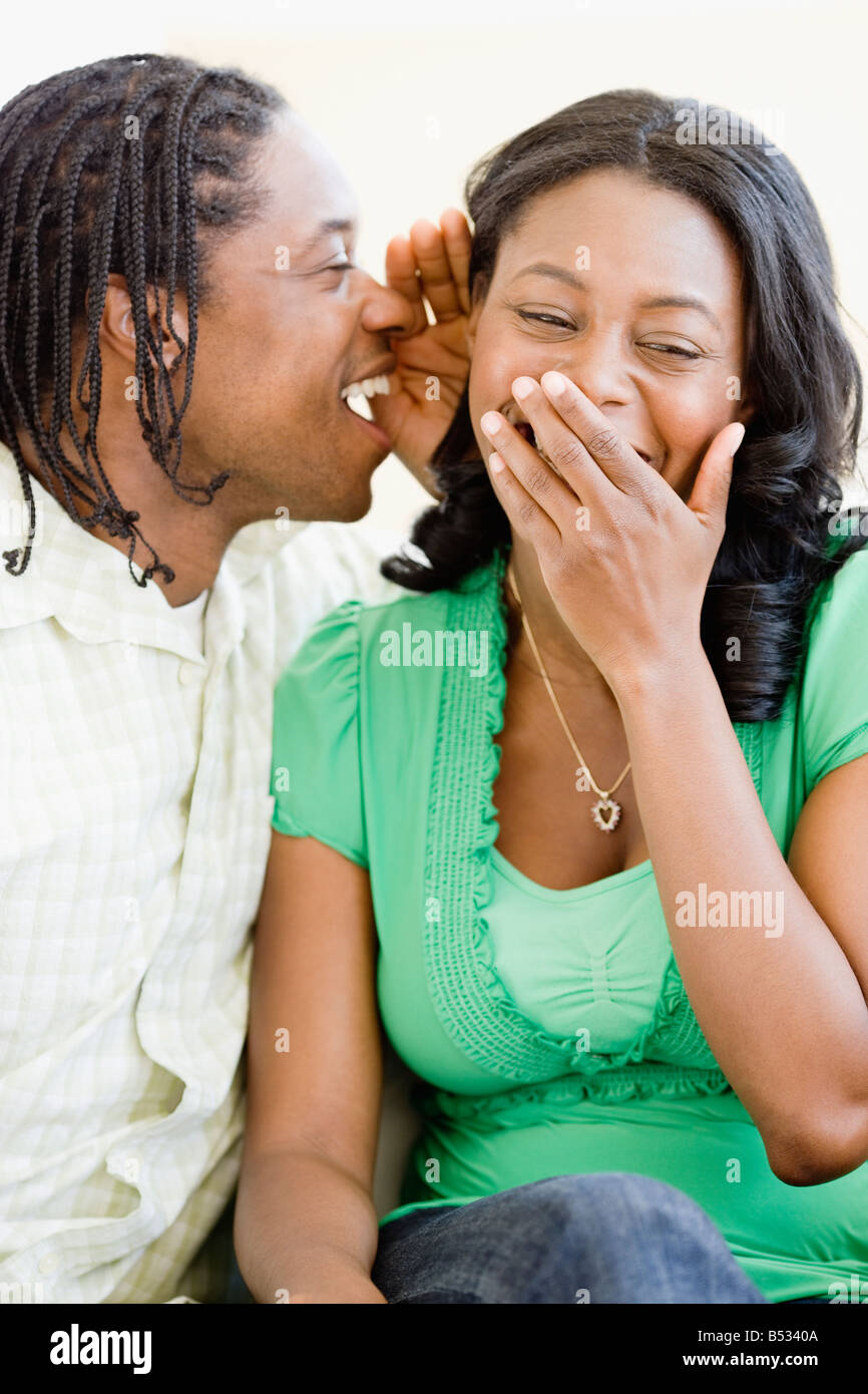 L'uomo africano whispering nella donna di orecchio Foto Stock