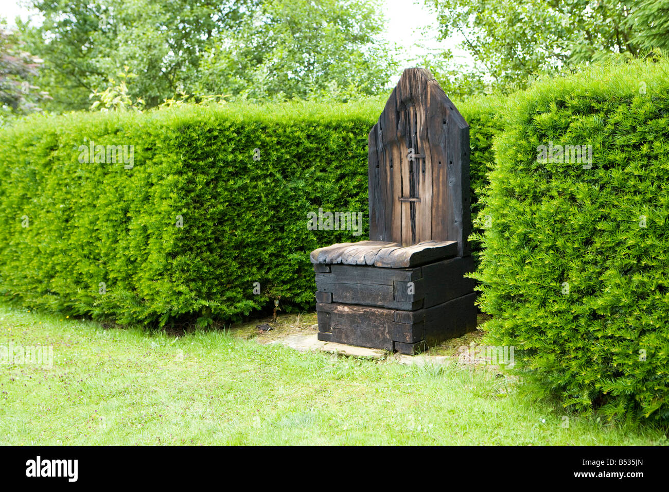 Grande trono di legno in un giardino con siepi di bosso Foto Stock