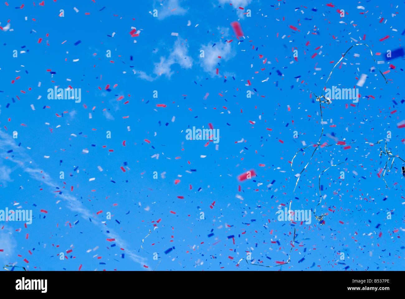 Abstract orizzontale del rosso bianco e blu-Ticker tape di esplodere in aria contro un luminoso cielo blu Foto Stock