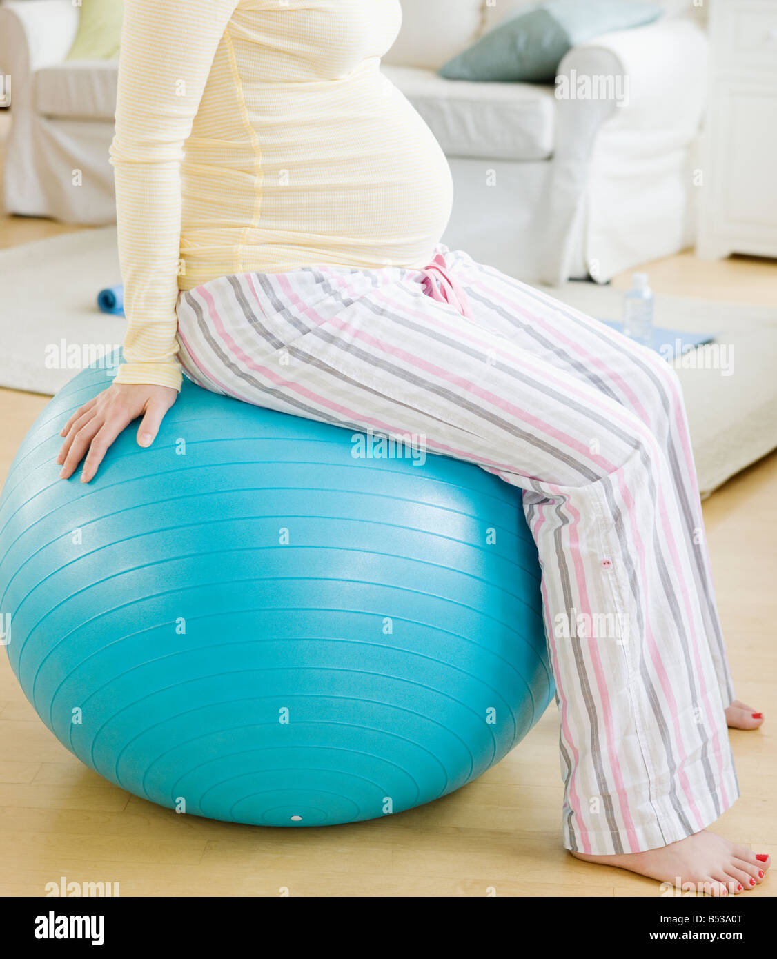 Incinta donna asiatica seduto su palla ginnica Foto Stock